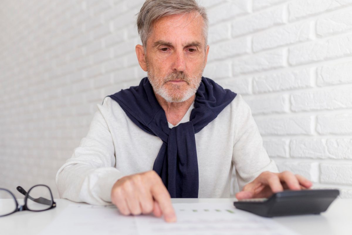  mężczyzna przeprowadzający wyliczenia na kalkulatorze